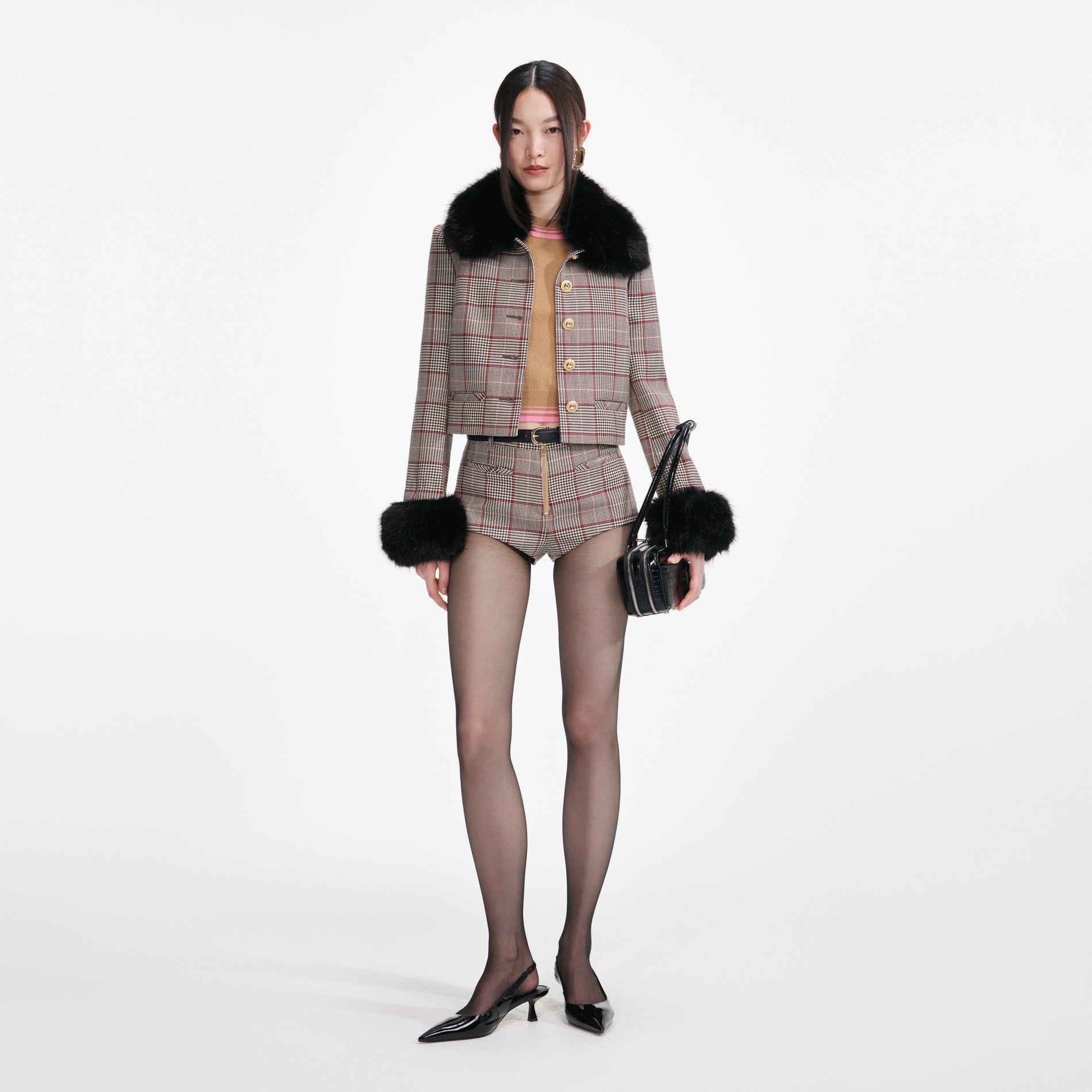 Woman in a brown plaid jacket with black fur trim, matching shorts, black tights, and black slingback heels