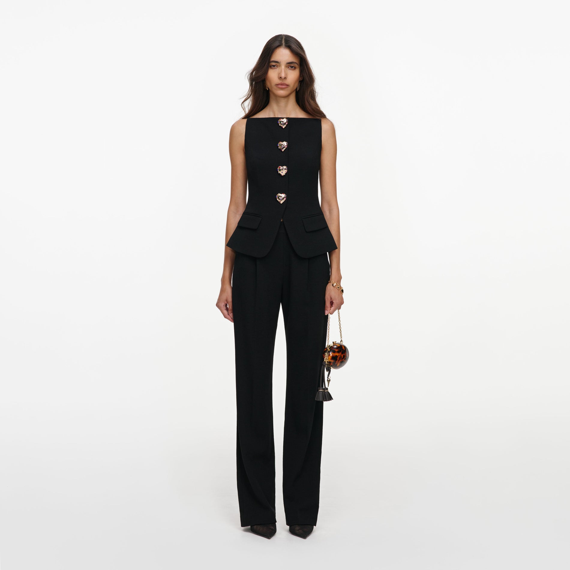 Woman in black sleeveless top with heart buttons and matching wide-leg trousers