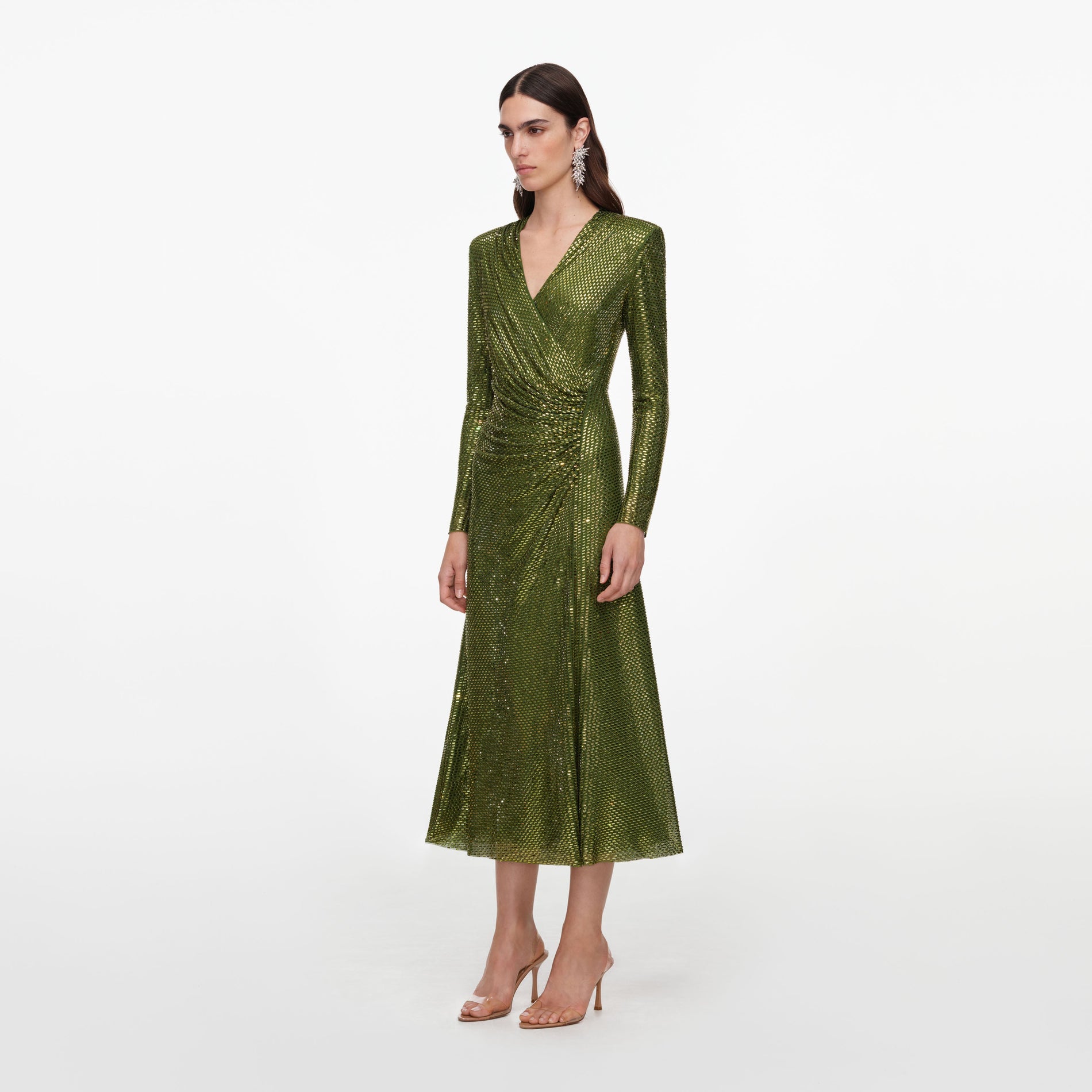 Woman in a long sleeve green metallic midi dress with a v-neckline and clear high heels