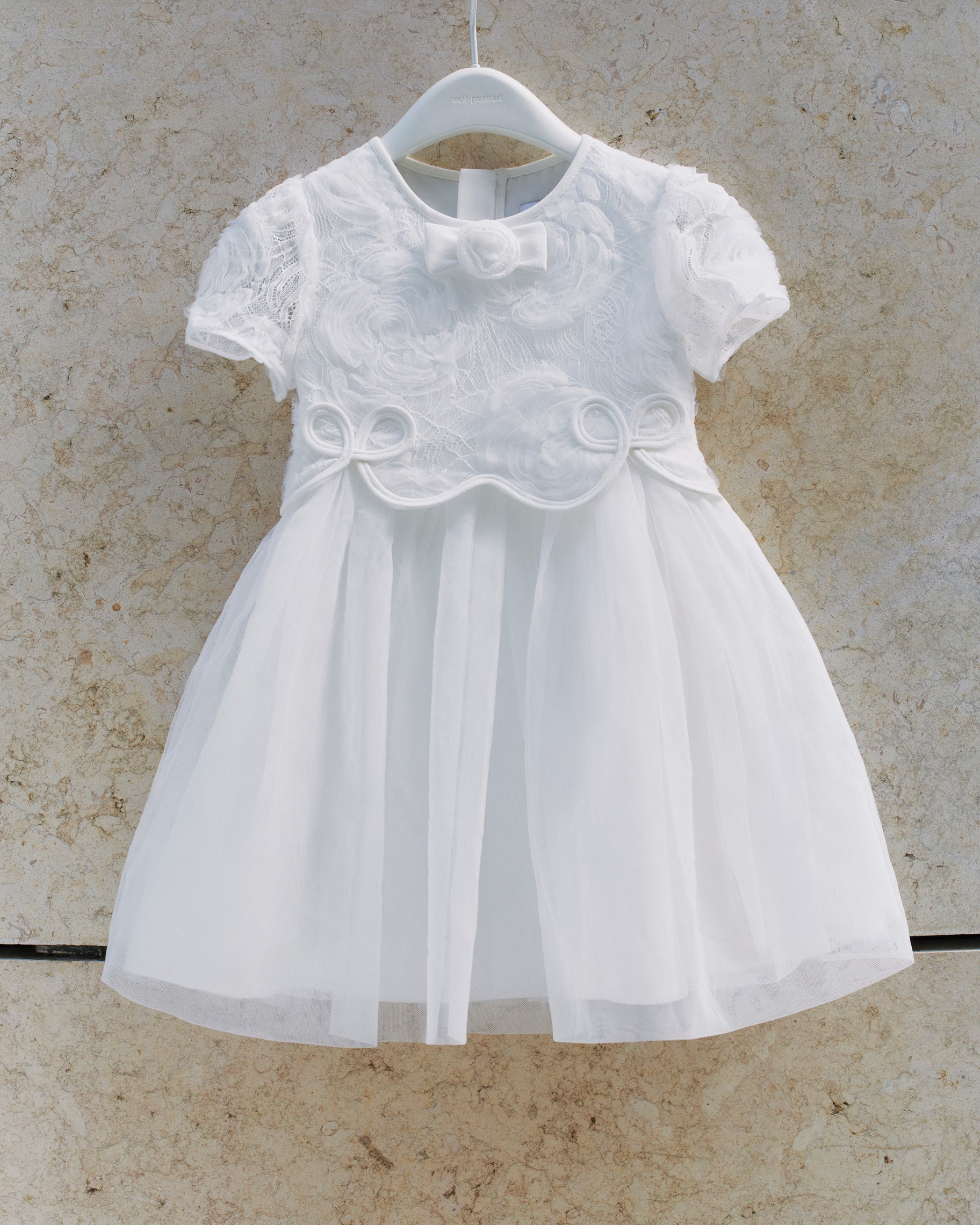 White lace and tulle dress with short sleeves and a bow detail on the neckline