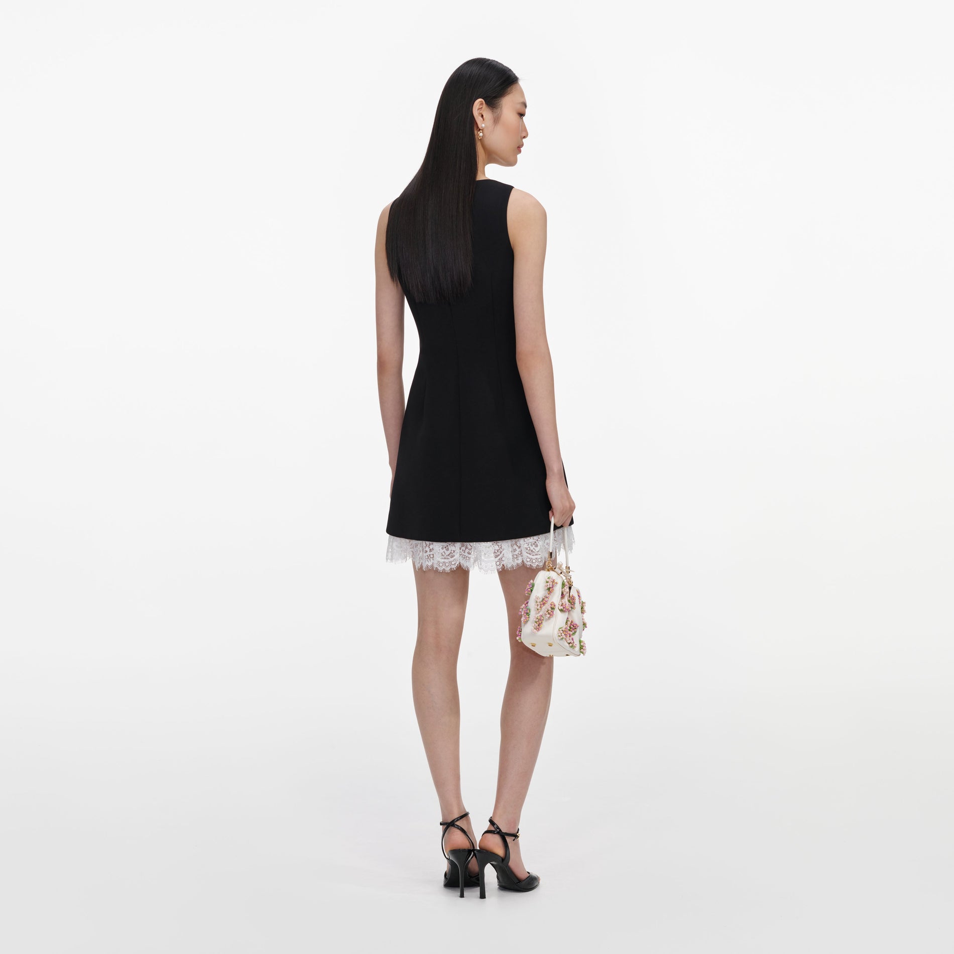 Back view of a woman wearing the Black Crepe Bow Lace Mini Dress