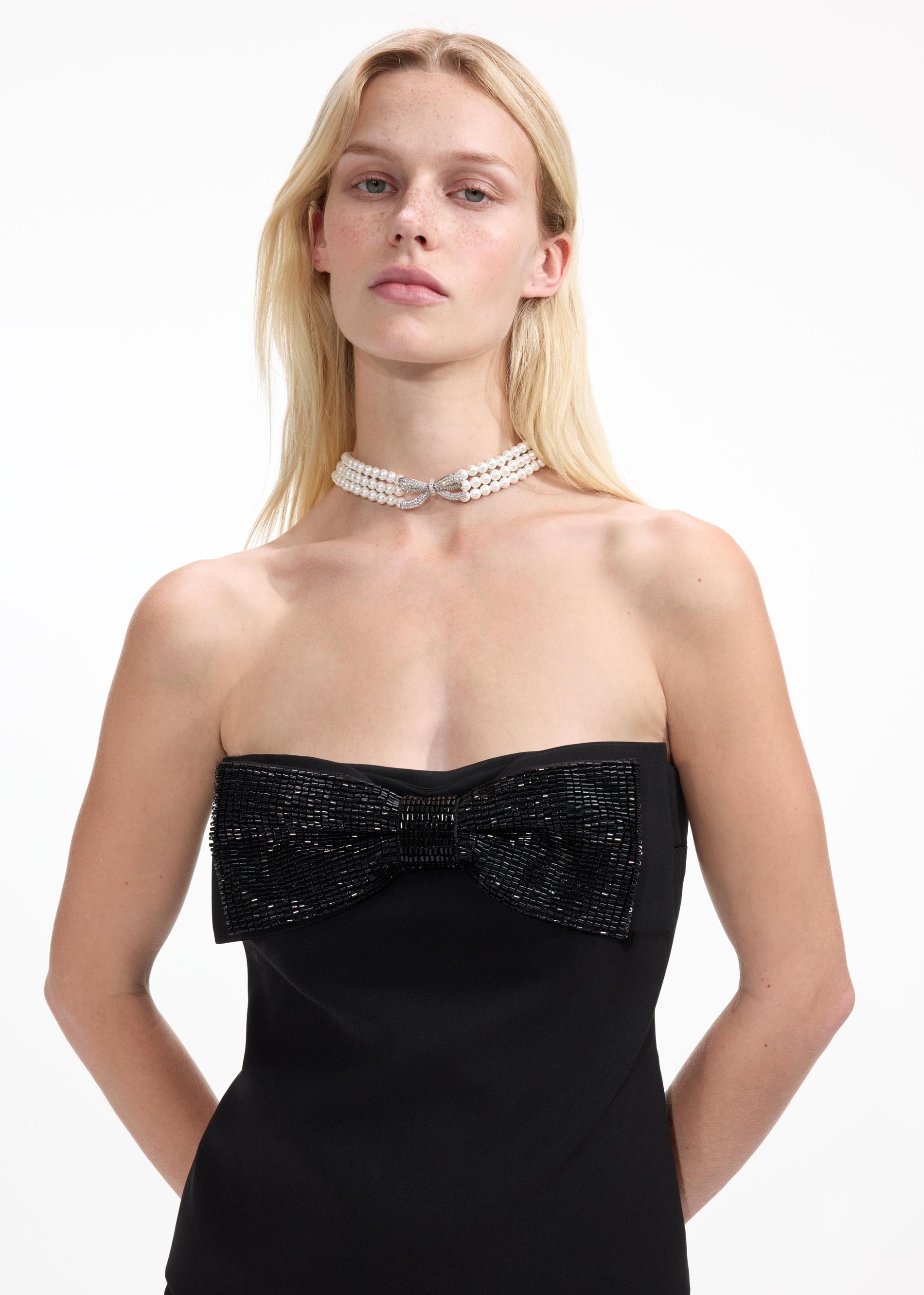 A close up of a woman wearing the Pearl Bow Choker