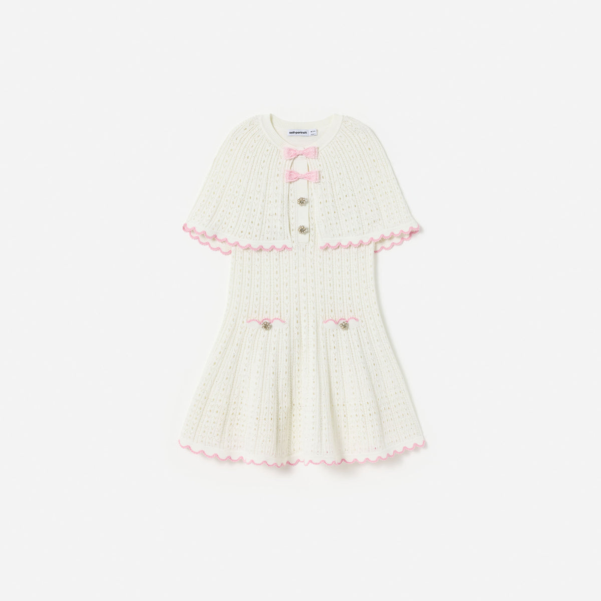 Front view of a girl wearing the White Pointelle Knit Bow Cape Dress