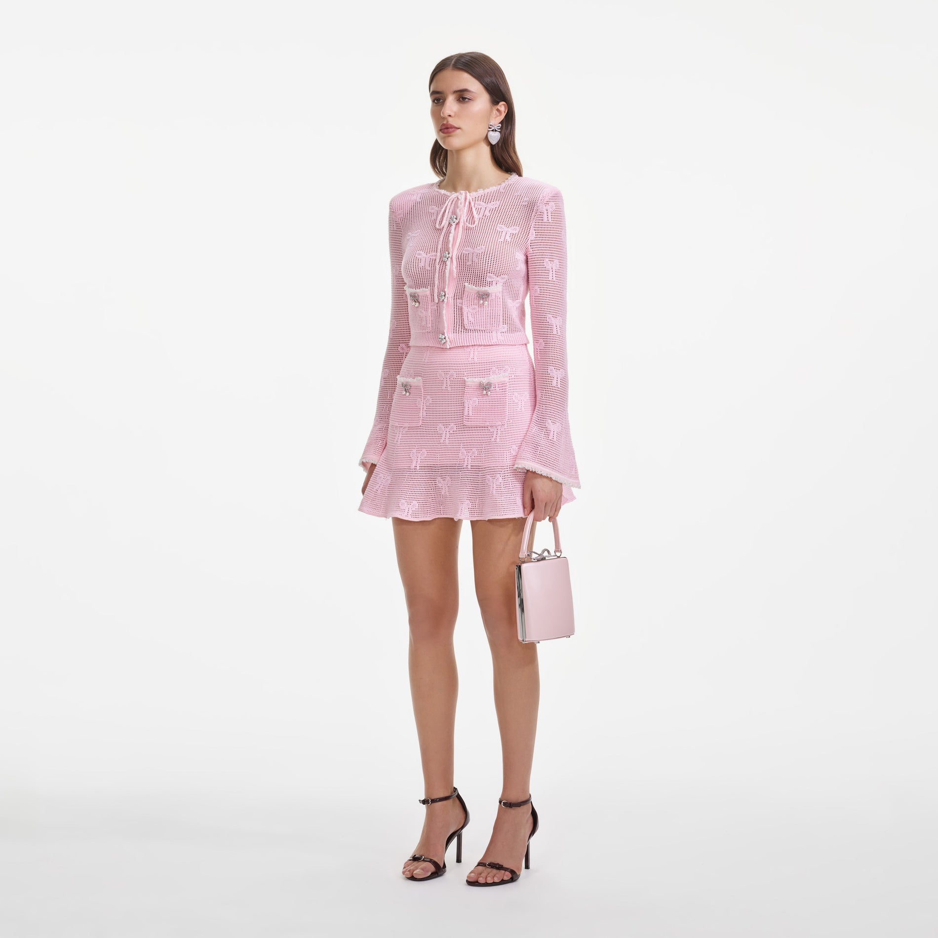 Side view of a woman wearing the Pink Bow Crochet Cardigan