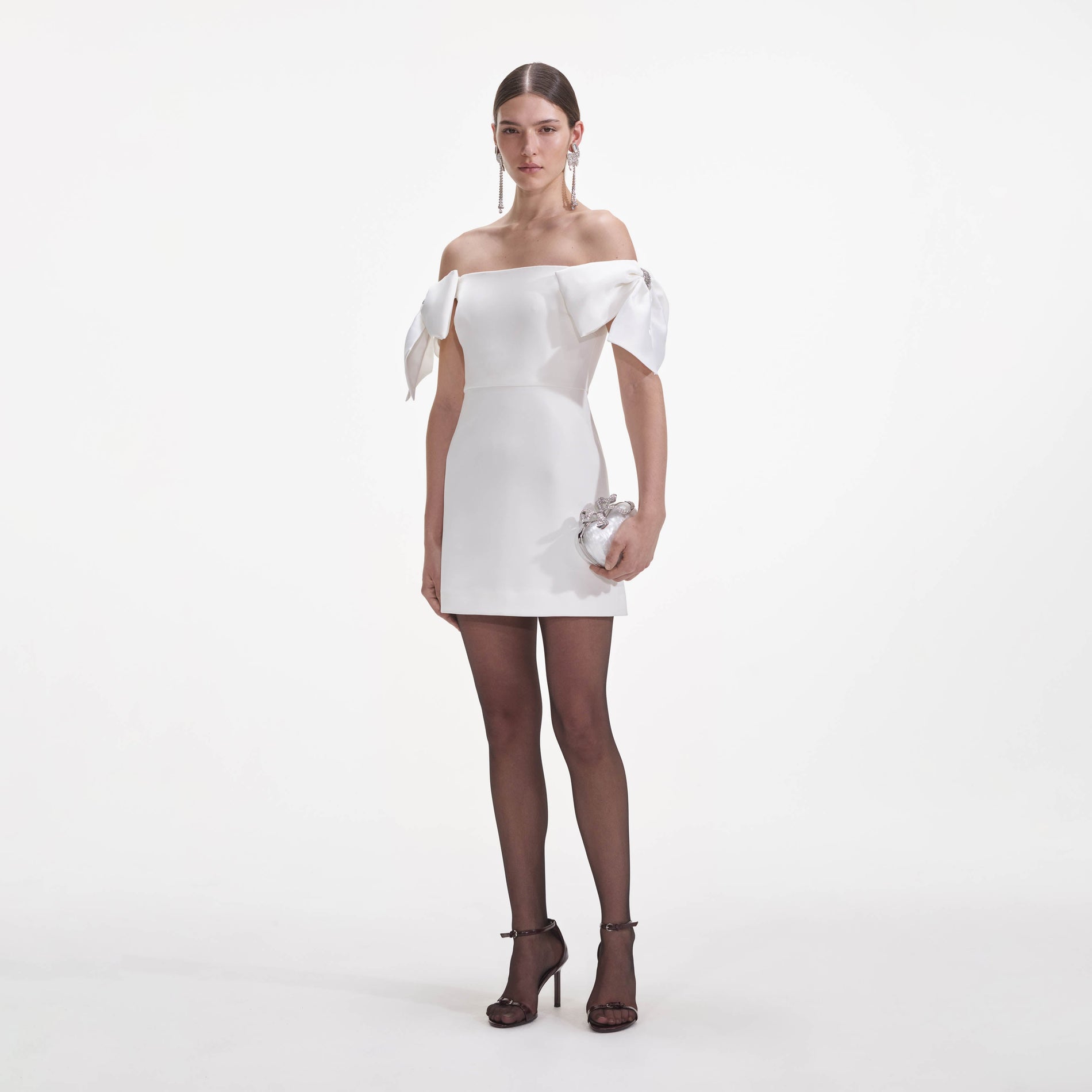 Side view of a woman wearing the White Crepe Bow Mini Dress