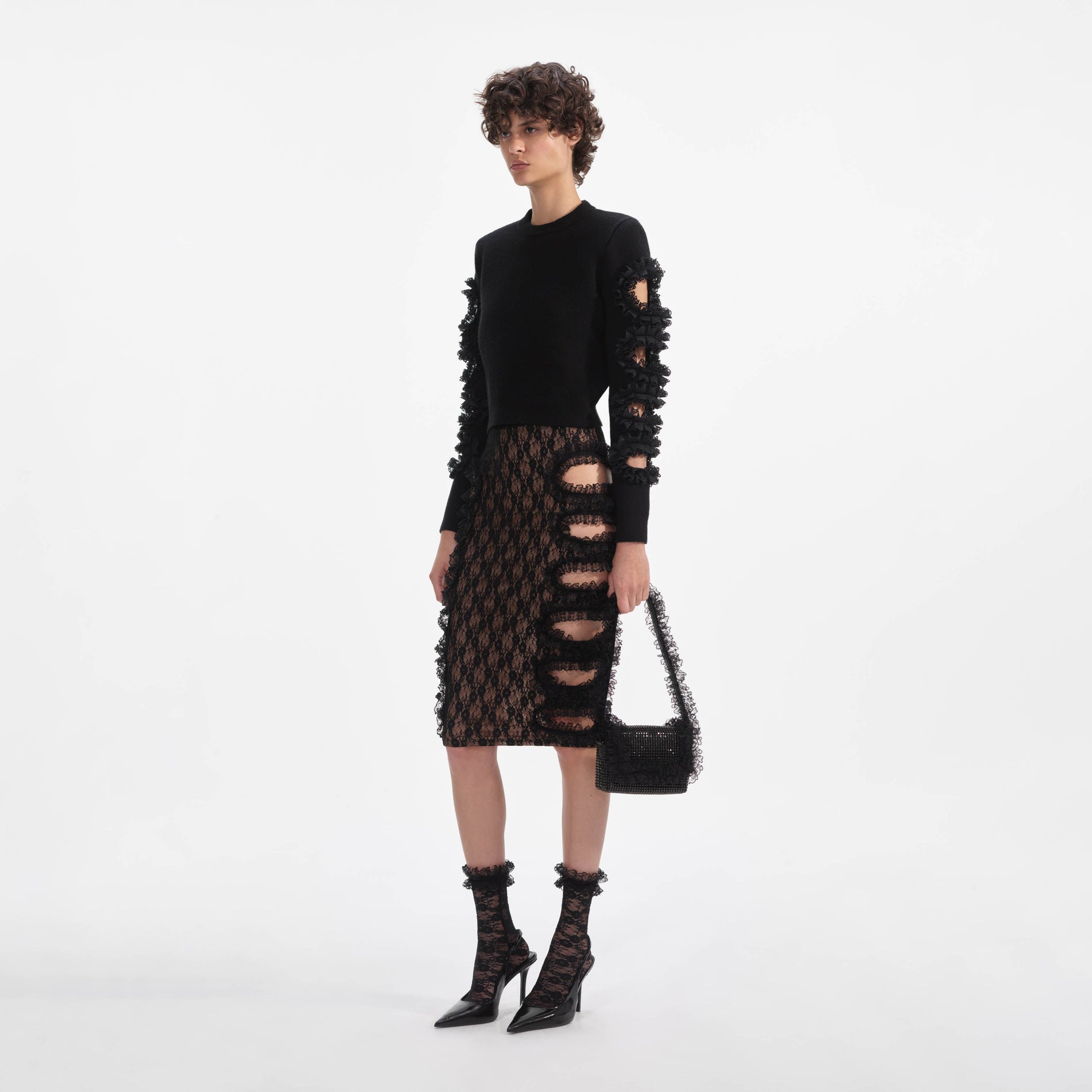 Side view of a woman wearing the Black Lace Cut Out Midi Skirt