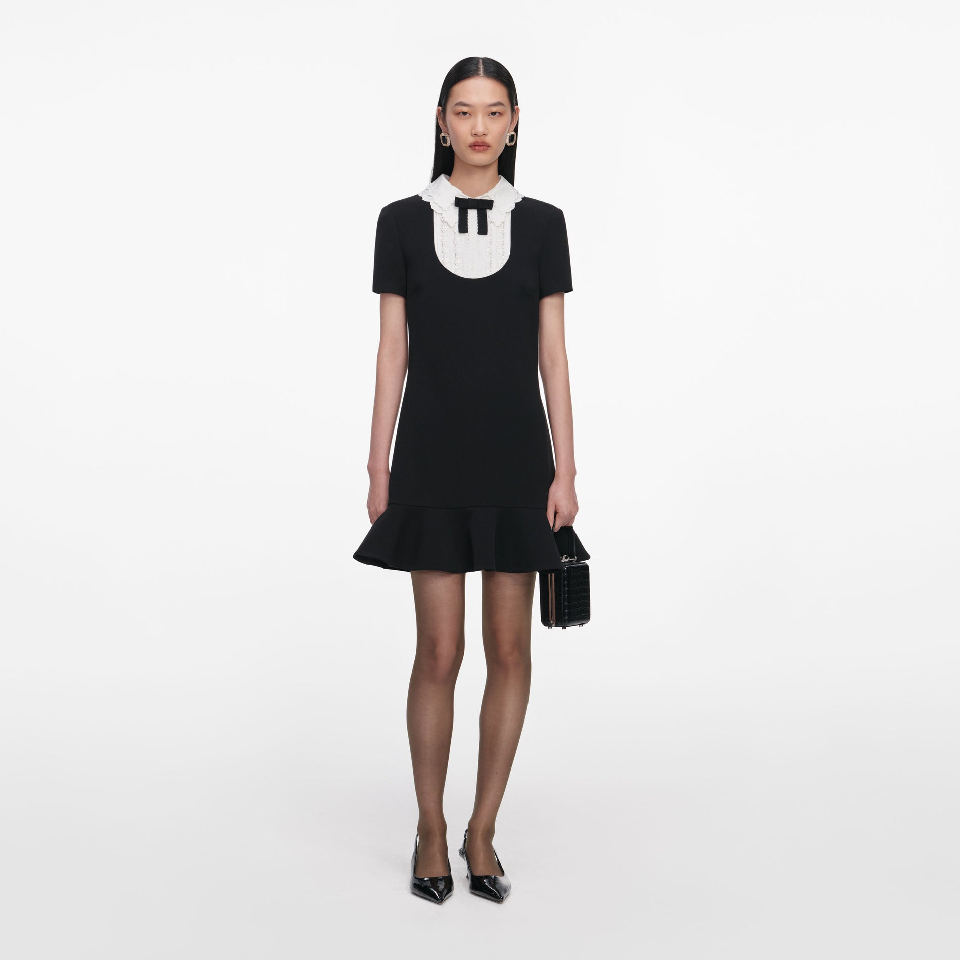 Front view of a woman wearing the Black Crepe Lace Bib Mini Dress