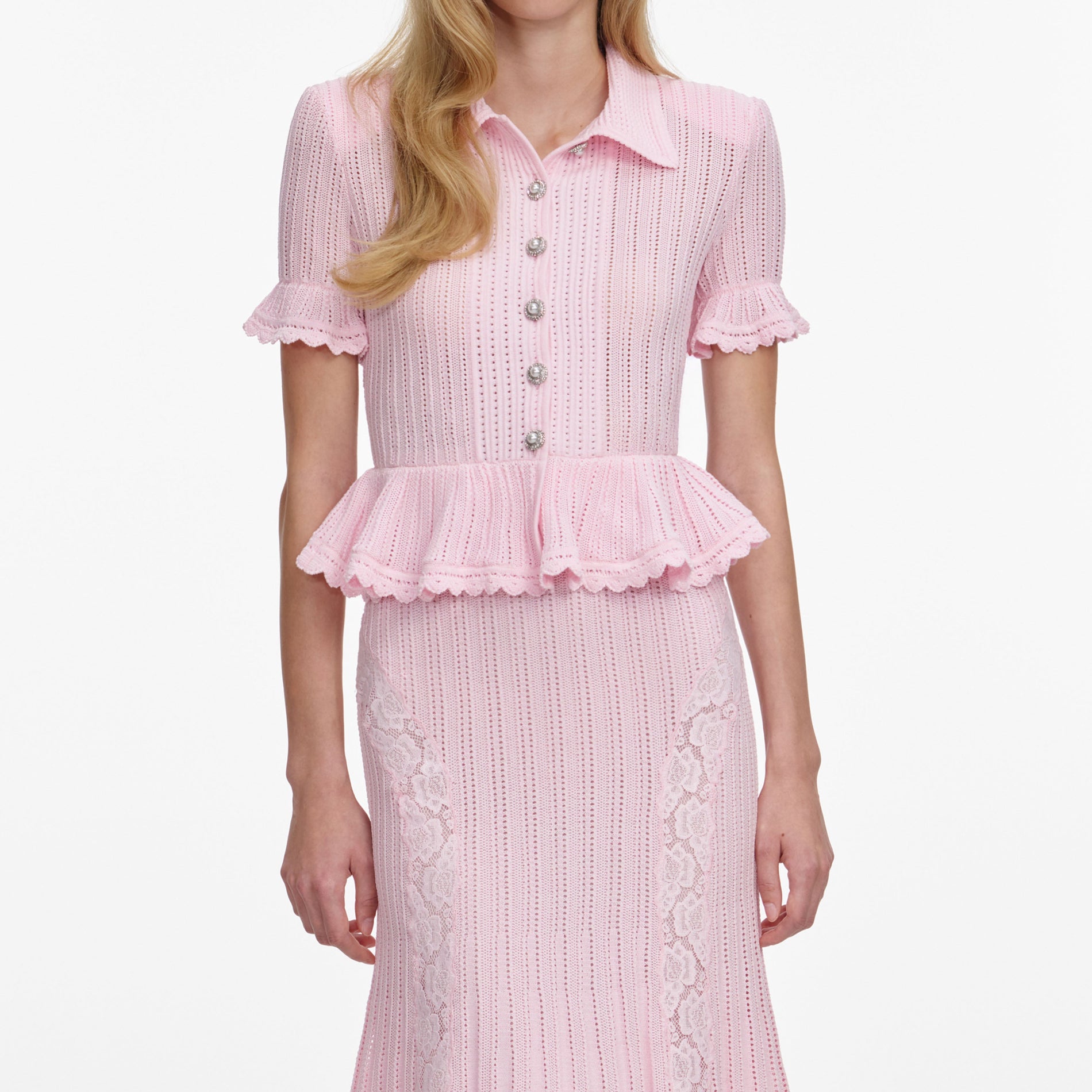 A close up of a woman wearing the Pink Pointelle Peplum Knit Midi Dress