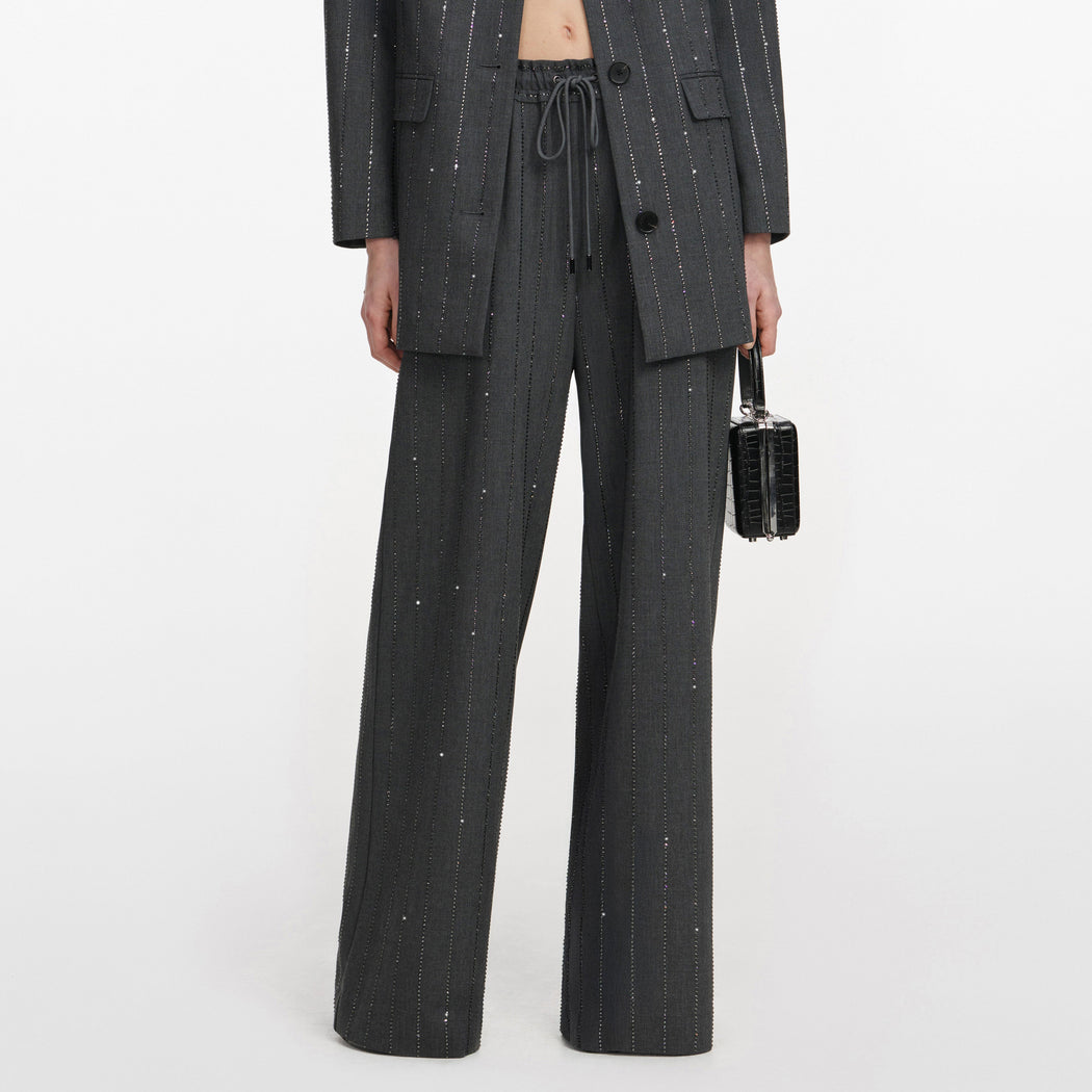 A close up of a woman wearing the Grey Rhinestone Pinstripe Trousers
