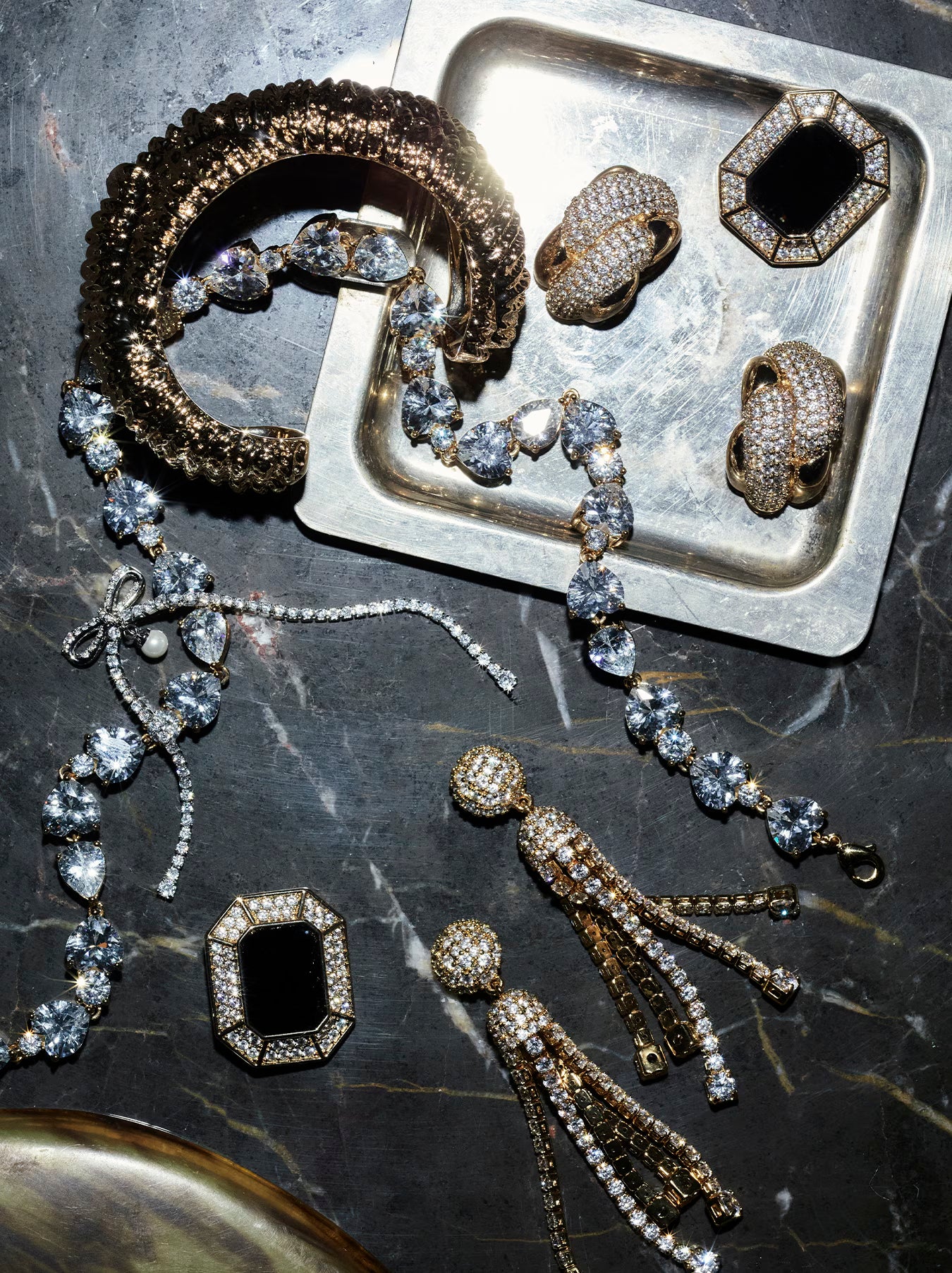 Jewellery set including rings, bracelet, and necklace on a dark surface with a metal tray.