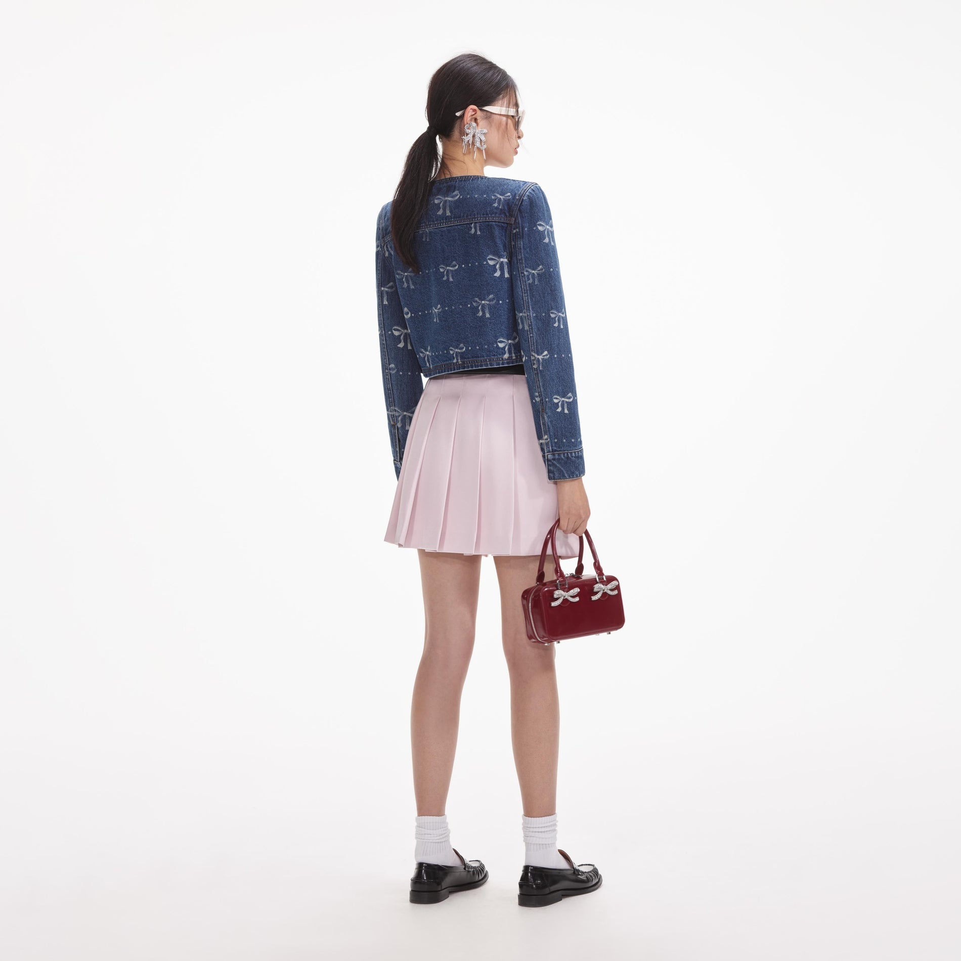 Back view of a woman wearing the White Bow Print Denim Jacket