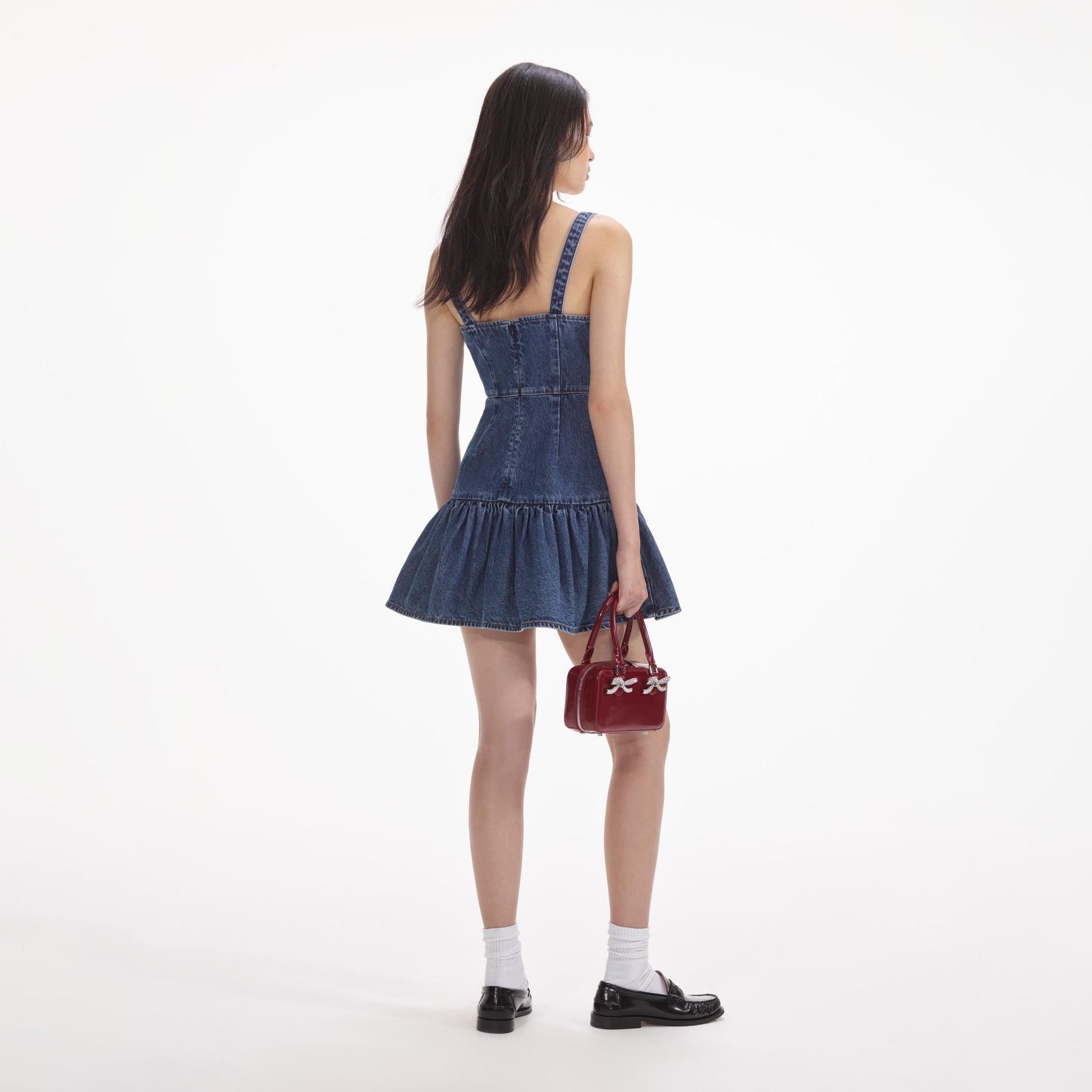 Back view of a woman wearing the White Bow Denim Mini Dress