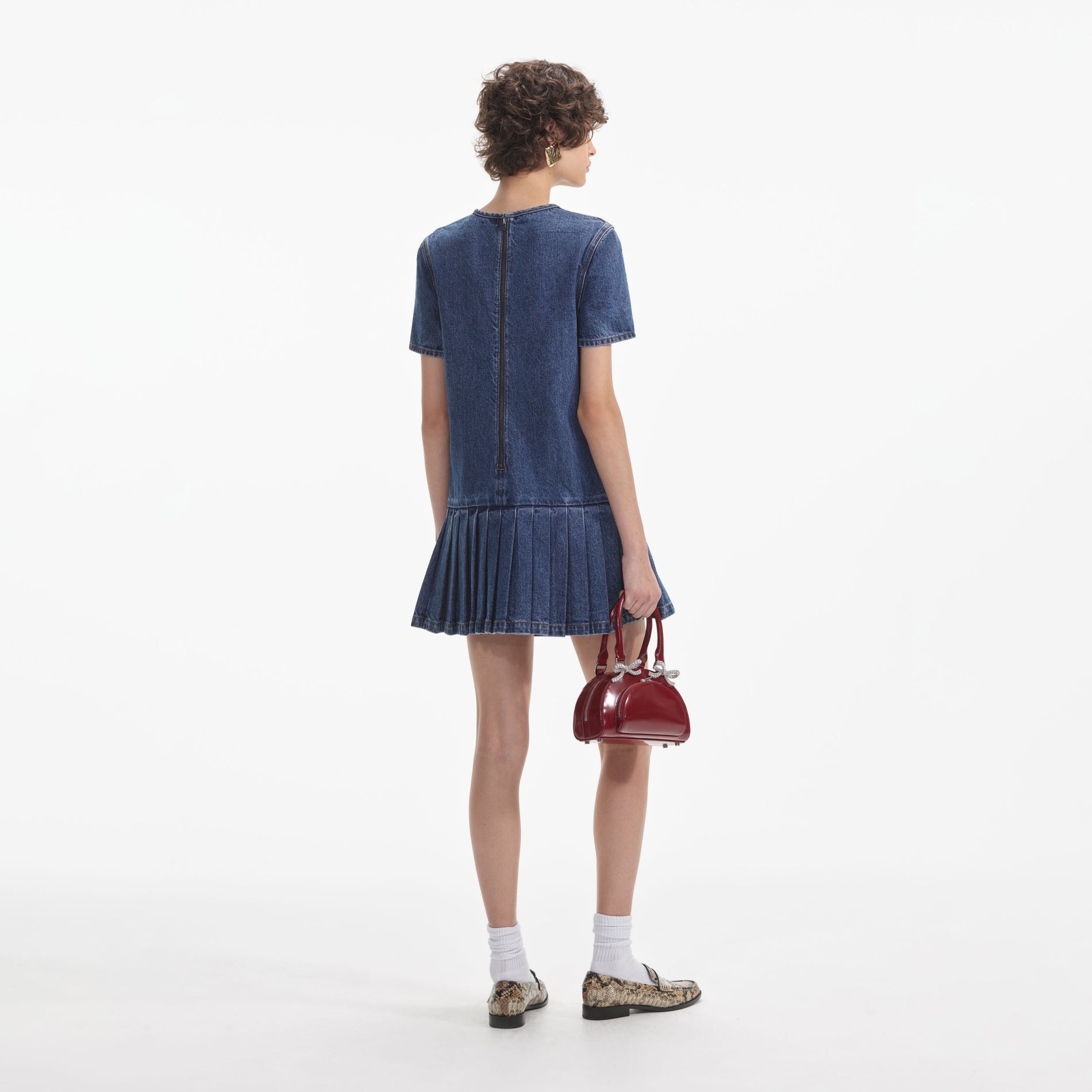 Back view of a woman wearing the White Pleated Denim Mini Dress