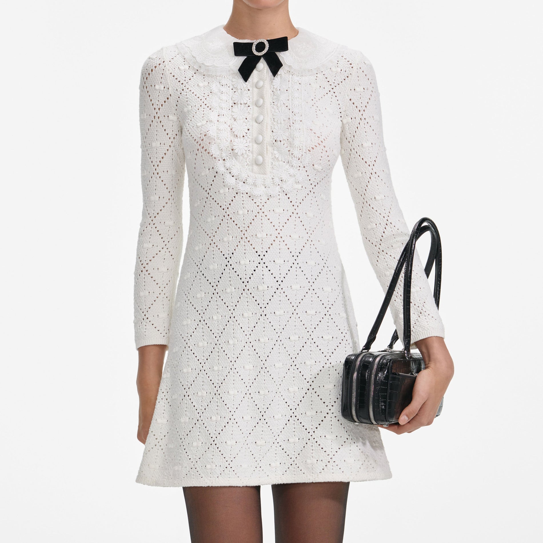 A close up of a woman wearing the White Lace Bib Knit Mini Dress
