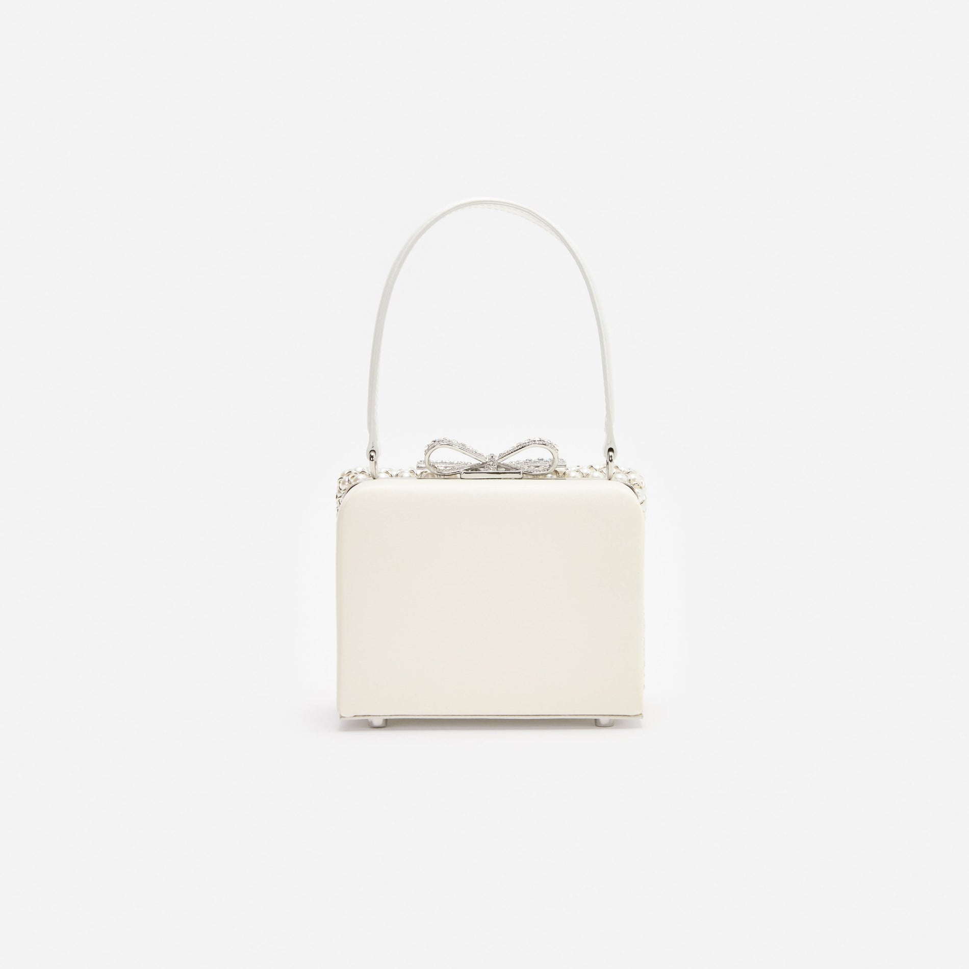 White handbag with a top handle and a crystal bow clasp
