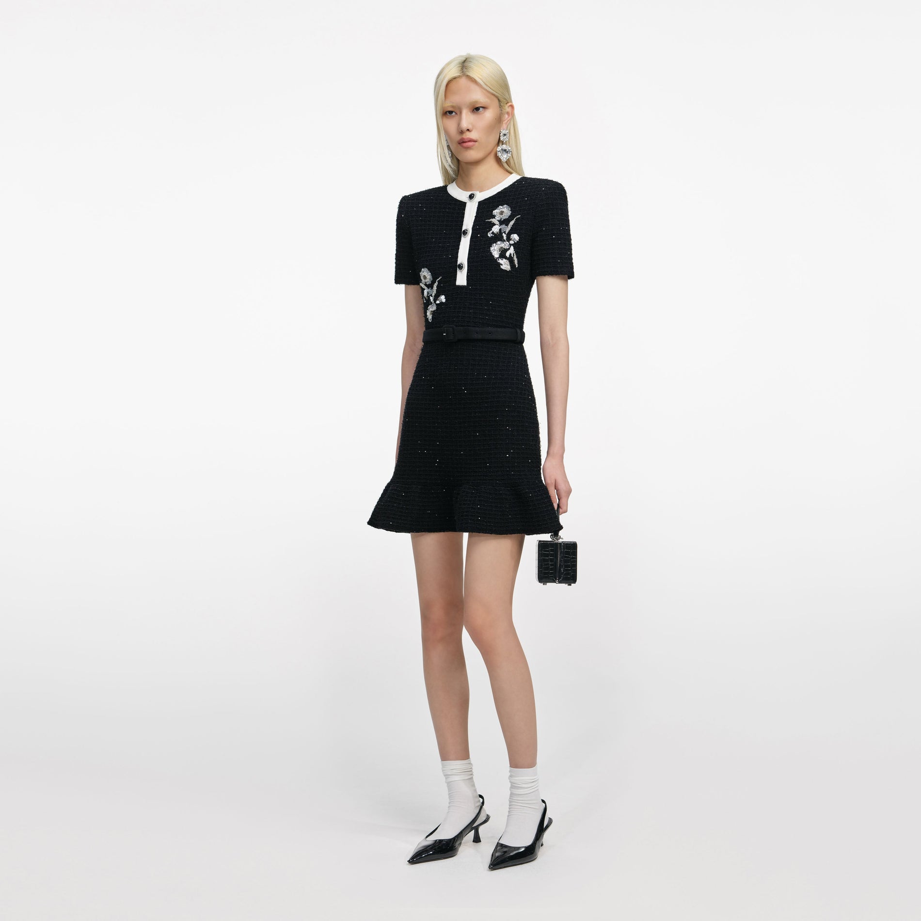 Side view of a woman wearing the Black Floral Textured Knit Mini Dress