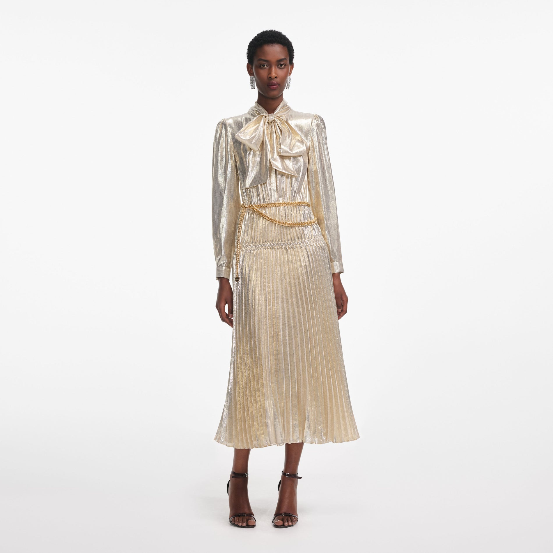 Front view of a woman wearing the Gold Metallic Pussy Bow Midi Dress