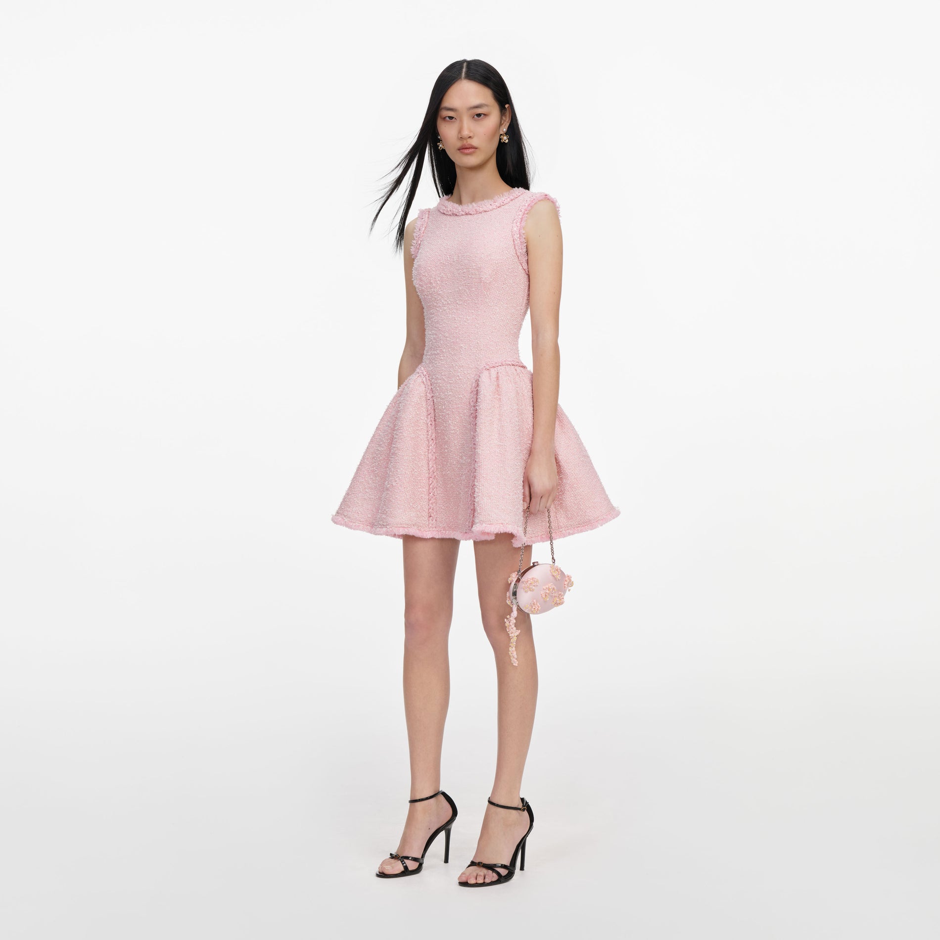 Woman in pink tweed mini dress, black high heels, and a small pink floral handbag