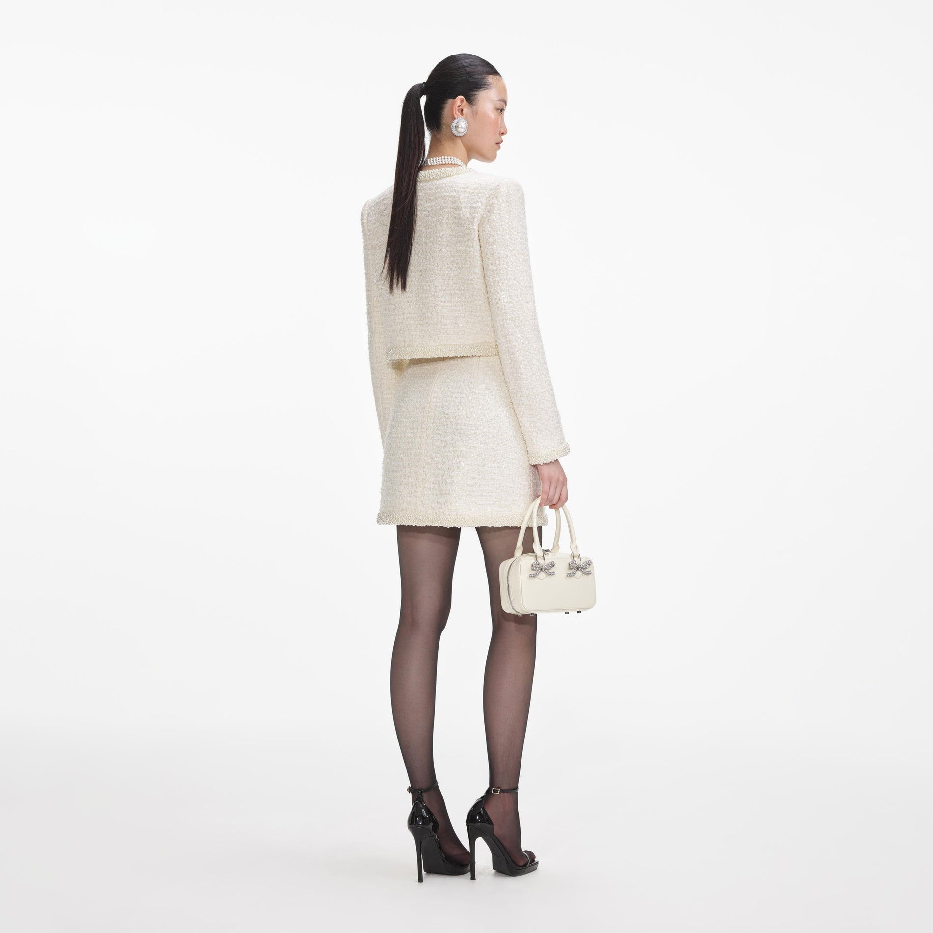 Back view of a woman wearing the Cream Boucle Pearl Trim Mini Skirt