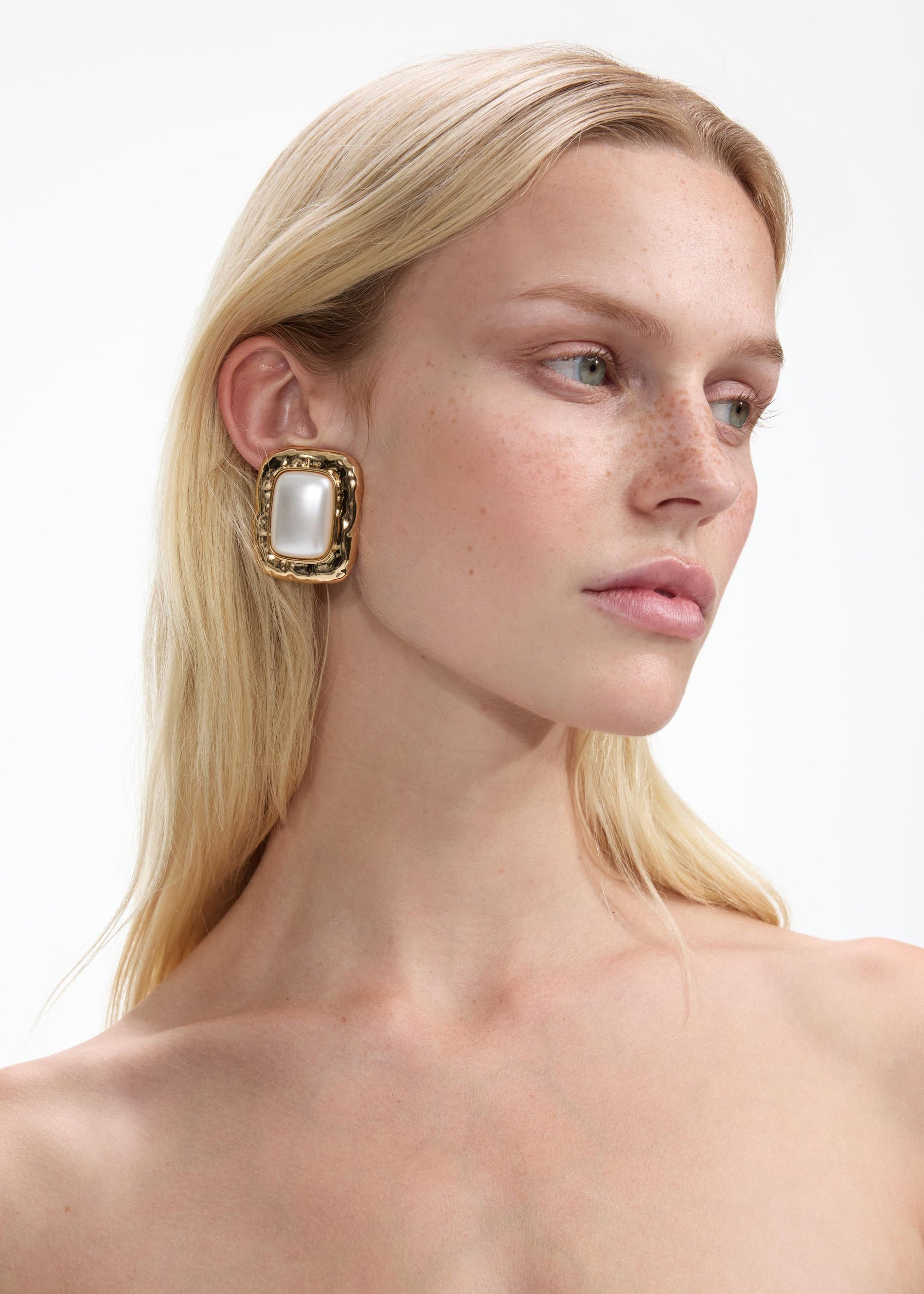A close up of a woman wearing the Mottled Gold Pearl Earrings