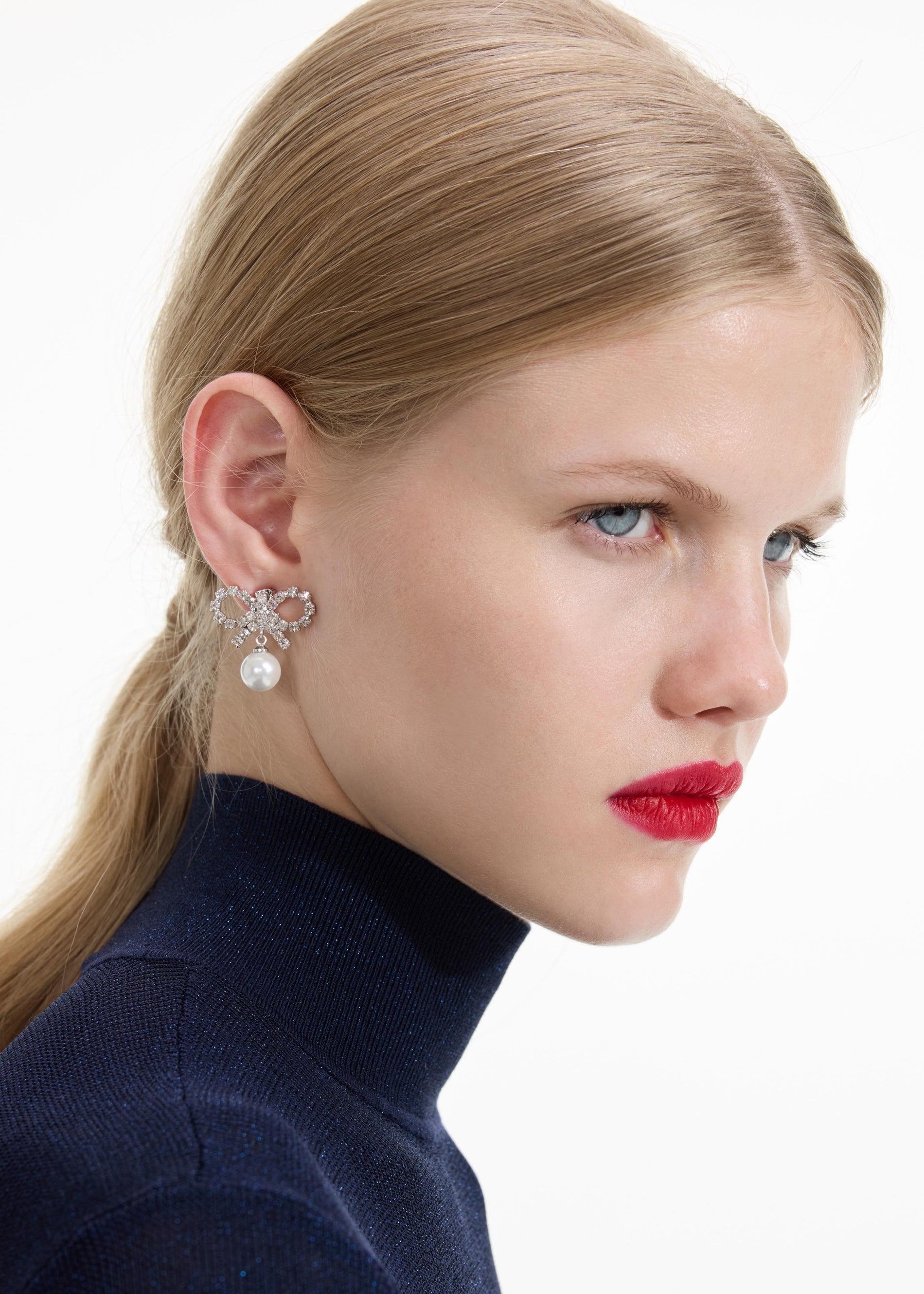 Back view of a woman wearing the Micro Bow Pearl Earrings